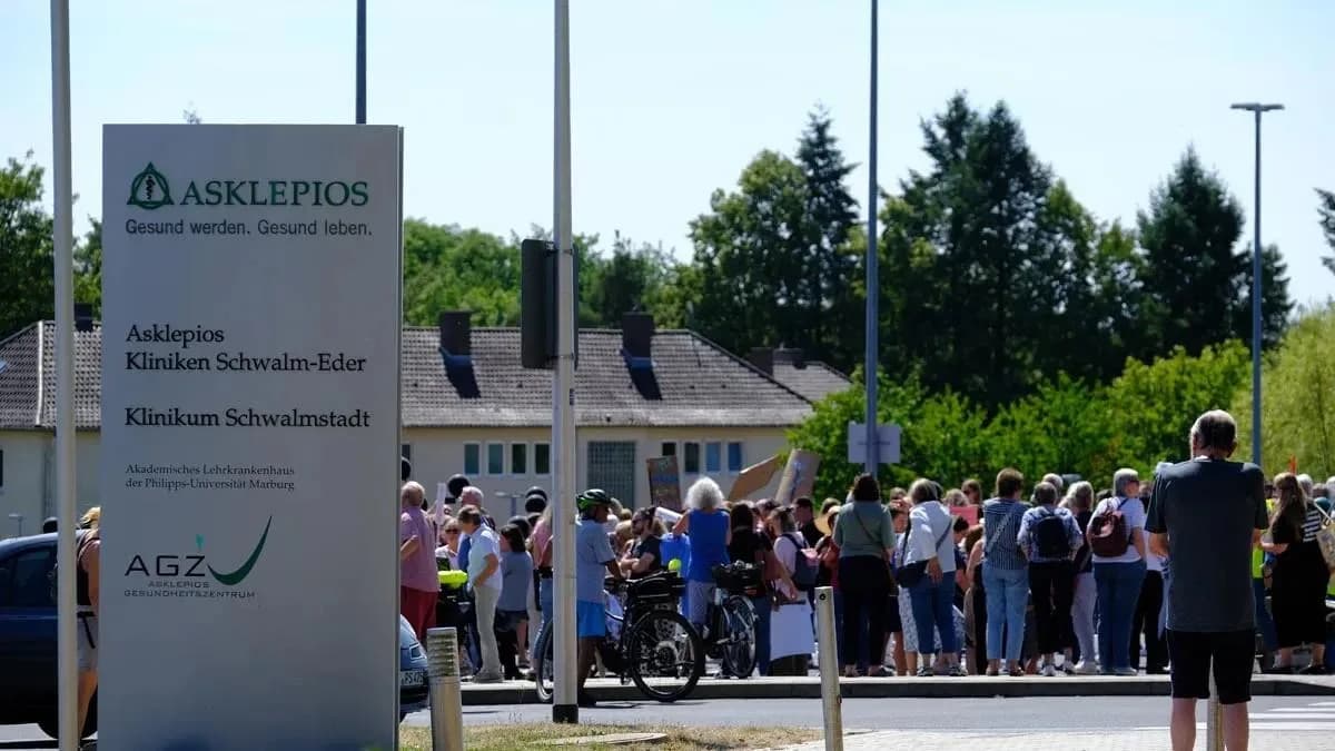 Das Hinweisschild „Asklepios Klinikum Schwalmstadt“, dahinter die Menschenmenge der Kundgebung.